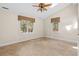 Bright bedroom featuring two windows, a ceiling fan, and tile flooring with a view of the private backyard at 3180 Pine Needle Ln, Seabrook Island, SC 29455
