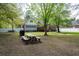 Private backyard with mature trees, wooden picnic table, and a white fence at 3708 Colonel Vanderhorst Cir, Mount Pleasant, SC 29466