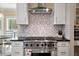 Close up of range and hood vent featuring mosaic backsplash and stainless steel appliances at 3708 Colonel Vanderhorst Cir, Mount Pleasant, SC 29466