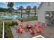 A community fire pit surrounded by coral Adirondack chairs, landscaping, and a pool at 384 Ripple Park Dr, Summerville, SC 29486