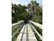 Inviting wooden walkway leading to the beach surrounded by lush tropical greenery and swaying palm trees at 4113 Buccaneer Rd, Isle of Palms, SC 29451