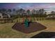 Fenced backyard play area at dusk with a mulch base, featuring a playset with a slide and swings for outdoor fun at 505 Kilarney Rd, Summerville, SC 29483