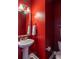 Stylish powder room with red walls, pedestal sink, modern fixtures, and elegant mirror at 545 Two Mile Run, Johns Island, SC 29455