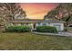 Charming one-story home with lush landscaping, brick walkway and inviting covered porch at sunset at 633 Schooner Rd, Charleston, SC 29412