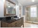 Stylish bathroom with dark vanity, framed mirror, and glass-enclosed shower, providing a luxurious feel at 1034 Orangeburg Rd, Summerville, SC 29483