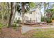 Beautiful two-story home with a metal roof and large wooden deck surrounded by lush landscaping and mature trees at 1034 Orangeburg Rd, Summerville, SC 29483