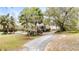 Scenic view of a home nestled among lush trees, featuring a curving driveway and verdant lawn at 1034 Orangeburg Rd, Summerville, SC 29483