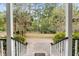View from a charming porch, framed by elegant columns and railings, overlooking a serene, wooded landscape at 1034 Orangeburg Rd, Summerville, SC 29483