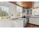 Kitchen with white cabinets, stainless steel appliances, wood ceiling, and view to backyard at 1034 Orangeburg Rd, Summerville, SC 29483
