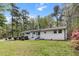 White brick house surrounded by tall trees and lush greenery. View from the front at 107 Woodland Dr, Summerville, SC 29485