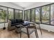 Enclosed porch provides a serene space with wicker furniture, natural light, and views of the lush, wooded surroundings at 107 Woodland Dr, Summerville, SC 29485