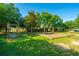 Community swingset with wooden swings and mulch on a grassy lot with lush green trees at 112 Tin Can Aly, Summerville, SC 29483