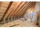 View of the unfinished attic with exposed wooden beams and a window, offering potential for customization at 1300 S Main St, Summerville, SC 29483