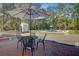 A brick patio has outdoor seating, an umbrella and overlooks the pool and yard at 1300 S Main St, Summerville, SC 29483