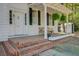Charming front porch with brick steps, hanging ferns, bench and a white door at 1300 S Main St, Summerville, SC 29483