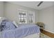 Bright bedroom featuring a bed with blue striped bedding, two windows with blinds and a wicker chair at 1504 Forrest Ave, Folly Beach, SC 29439