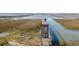 View of a gated pier extending into the marshland and open water on a sunny day at 1504 Forrest Ave, Folly Beach, SC 29439