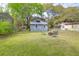 View of a spacious, grassy backyard with a fire pit and seating, surrounded by mature trees at 1617 Balsam St, Charleston, SC 29407