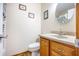 Well-lit bathroom with a wooden vanity, light countertop, modern toilet, and decorative wall art at 220 New Oak Ln, Moncks Corner, SC 29461
