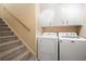 Well-lit laundry room with white washer and dryer, storage cabinets, and access to the carpeted staircase at 234 Lipman St, Summerville, SC 29483
