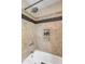 A tub and shower with tan and black tiles, a showerhead, and a built-in soap shelf at 28 Rebellion Rd, Charleston, SC 29407