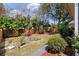 Manicured backyard with a wooden fence, garden beds, mature trees, and lush landscaping at 2940 Amberhill Way, Charleston, SC 29414