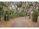 Long driveway with gated entrance leads to a secluded property amidst a canopy of trees and natural foliage at 3110 Up Da Creek Ct, Seabrook Island, SC 29455