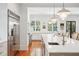 Bright kitchen with stainless steel fridge, kitchen island with white stone countertop, sink, and hardwood floors at 34 Frogmore Rd, Mount Pleasant, SC 29464