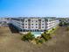 Aerial view of a multi-story condo building with a pool and surrounding landscape, offering resort-style living at 3701 Dock Site Rd # 302, Edisto Beach, SC 29438