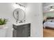 Updated bathroom featuring a vanity with sleek fixtures, round mirror, and a view into the bedroom at 4757 June St, North Charleston, SC 29405