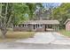 Well-maintained one-story brick home featuring a covered parking area, mature trees, and lawn at 4757 June St, North Charleston, SC 29405