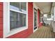 Inviting front porch with red siding, white trim, and wood flooring at 490 Sanders Farm Ln, Charleston, SC 29492