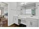 Bright bathroom with white cabinets, dual sinks, large mirror, and plantation shutters on the window at 5254 Mulholland Dr, Summerville, SC 29485