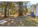 Spacious backyard with tall trees, and the rear of the house with a staircase and small deck at 5638 Dixie Plantation Rd, Hollywood, SC 29449