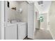 Bright laundry room with white washer, dryer, shelving, and adjacent hallway at 601 Buckthorn Cir, Summerville, SC 29483