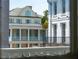 Charming Charleston home featuring white columns, aqua shutters, and a balcony, framed by a window view at 61 Tradd St, Charleston, SC 29401