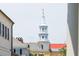 View of the historic downtown clock tower peaking over a roofline, framed between two porch columns at 61 Tradd St, Charleston, SC 29401