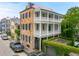 An exterior elevation featuring a two-story home with double porches, lush landscaping, and wrought iron gate at 61 Tradd St, Charleston, SC 29401