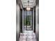 Hallway featuring black grid-paned doors, checkerboard flooring, and elegant lighting fixtures at 61 Tradd St, Charleston, SC 29401
