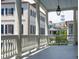 A covered porch features a lantern, classic columns and white railings with a view of historic Charleston at 61 Tradd St, Charleston, SC 29401