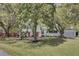 Charming white house with red doors, black shutters, and mature trees gracing the front yard, offering a welcoming feel at 703 Canary Dr, Charleston, SC 29414