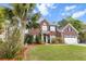 Exterior home view showcasing lush landscaping, brick facade, two-car garage, and American flag at 9411 Harroway Rd, Summerville, SC 29485