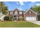 Traditional brick two-story home with a two-car garage, American flag, and well-maintained landscaping at 9411 Harroway Rd, Summerville, SC 29485