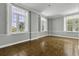 Light-filled living room features hardwood floors and multiple windows with plantation shutters at 1 King St # 209/210, Charleston, SC 29401