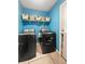 Modern laundry room with front loading washer and dryer, blue walls and shelving for storage at 103 Beverly Dr, Ladson, SC 29456