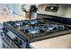 Close-up of a modern black and stainless steel stove with four burners on a white countertop at 1132 Mossy Rock Dr, Summerville, SC 29485
