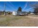 Exterior of the house showcases a spacious lot, mature trees, and a quaint sunroom extension at 126 N Hwy 52, Moncks Corner, SC 29461