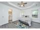 Comfortable main bedroom with a tray ceiling, ceiling fan, light gray flooring, and adjacent bathroom at 1312 Belle Grove Cir, Hanahan, SC 29410