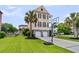 Home exterior featuring a two-car garage, palm trees, and a basketball hoop at 138 Sandshell Dr, Charleston, SC 29492