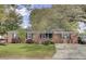 Traditional brick home with well-manicured lawn, mature trees and black shutters on windows at 1406 Iroquois St, North Charleston, SC 29405